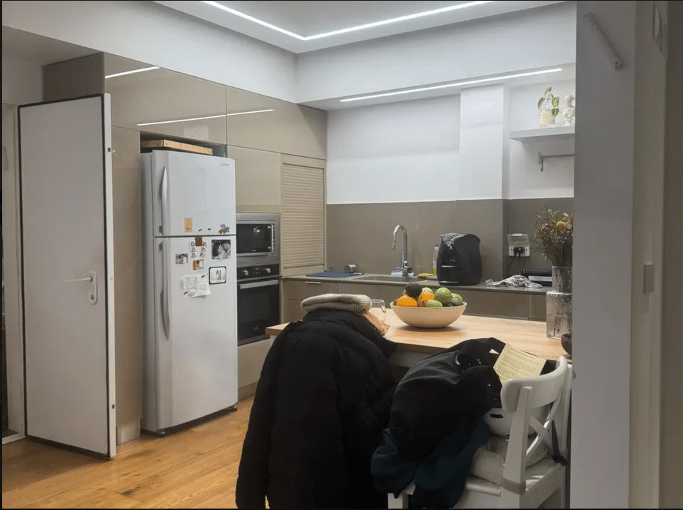 Modern kitchen with built-in appliances and wood dining counter in Tel Aviv apartment