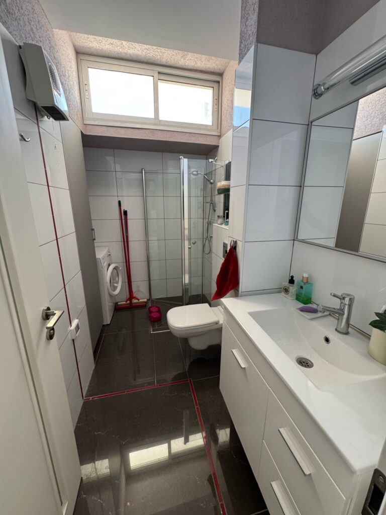 Renovated bathroom with glass shower and laundry area