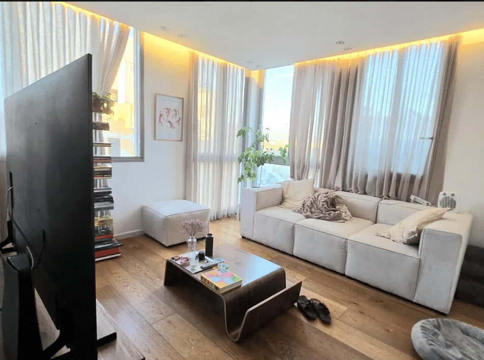 Bright living room with large windows and wood flooring in Tel Aviv apartment