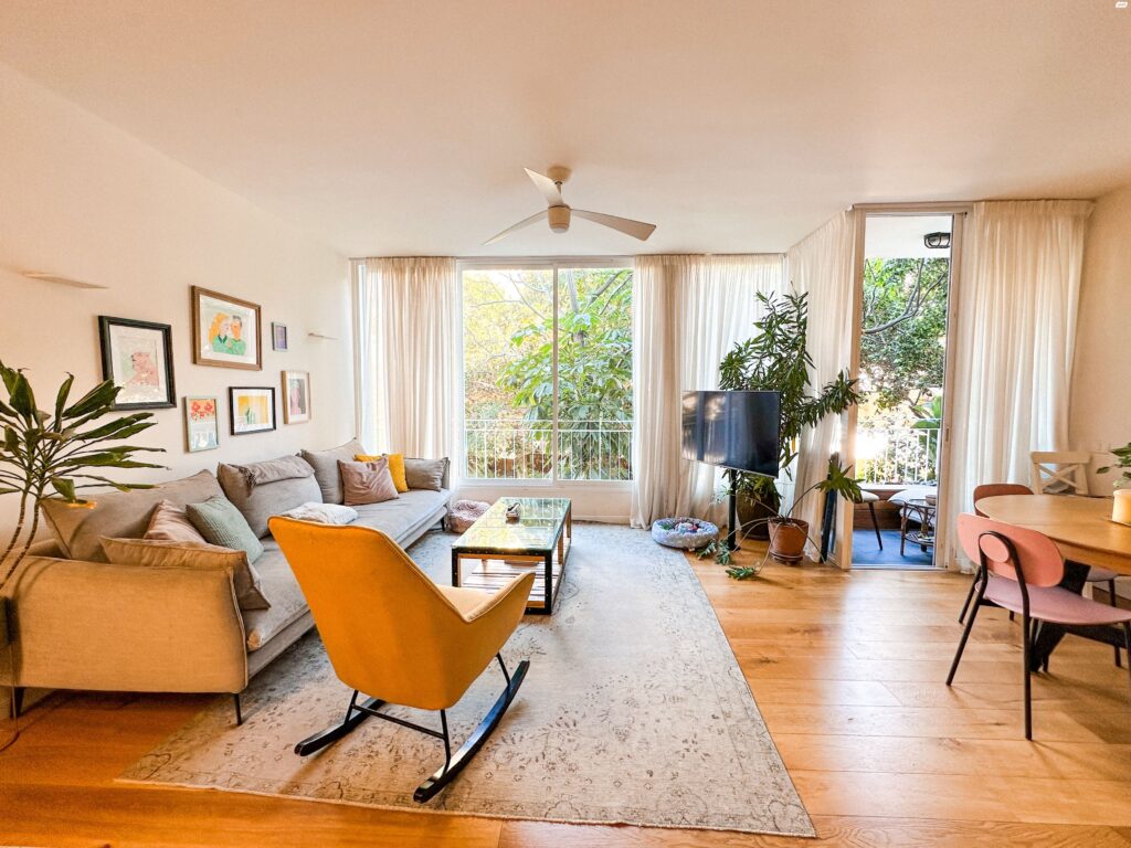 Living room and balcony in renovated 3-room Tel Aviv apartment