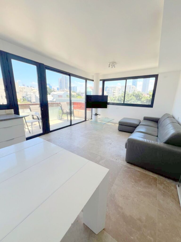 Bright living room with floor-to-ceiling windows and city views in Tel Aviv penthouse