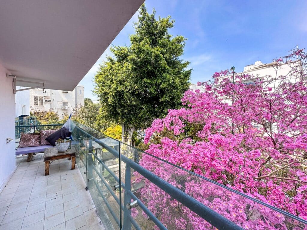 Spacious balcony surrounded by lush greenery and pink flowers