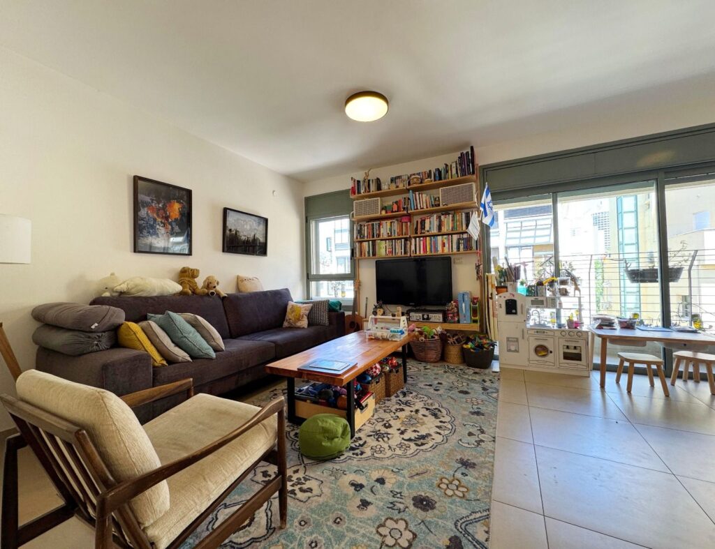 Living room with large sofa, bookshelves, and balcony access