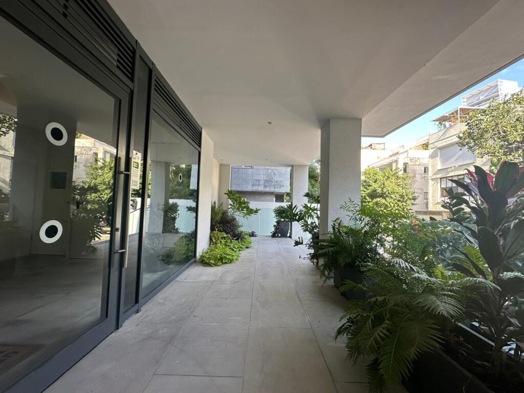 Entry walkway of modern Tel Aviv apartment building with greenery