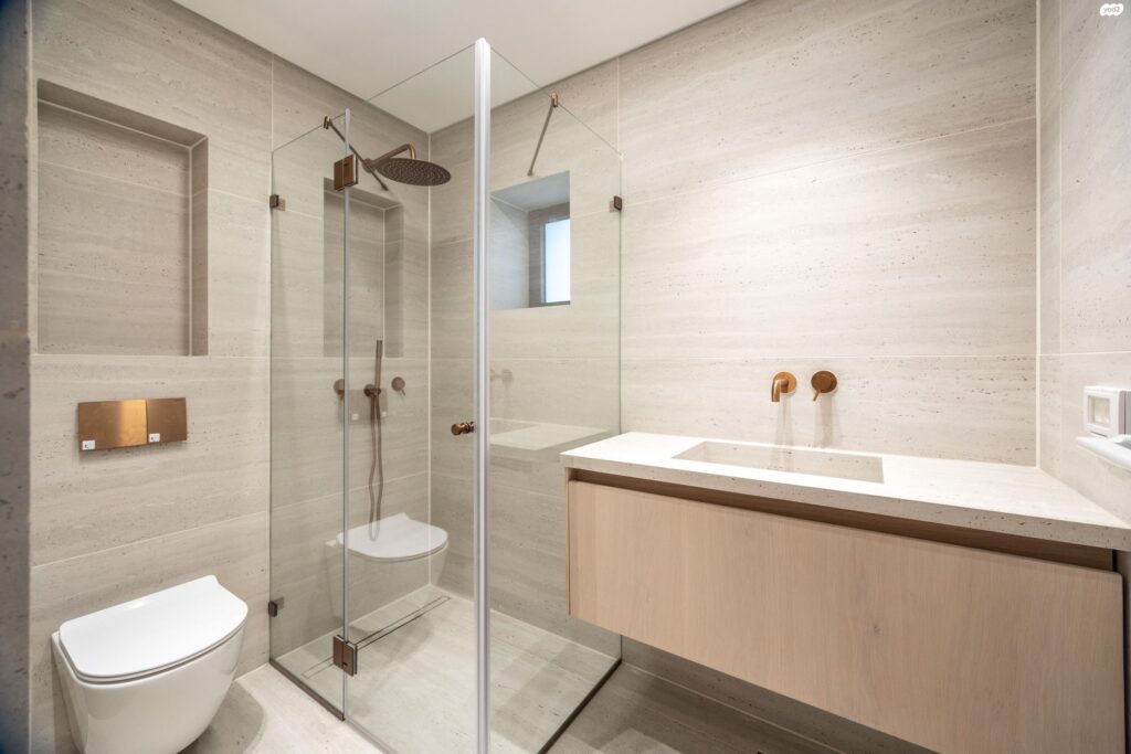 Modern bathroom with natural stone and brass fixtures in Tel Aviv apartment