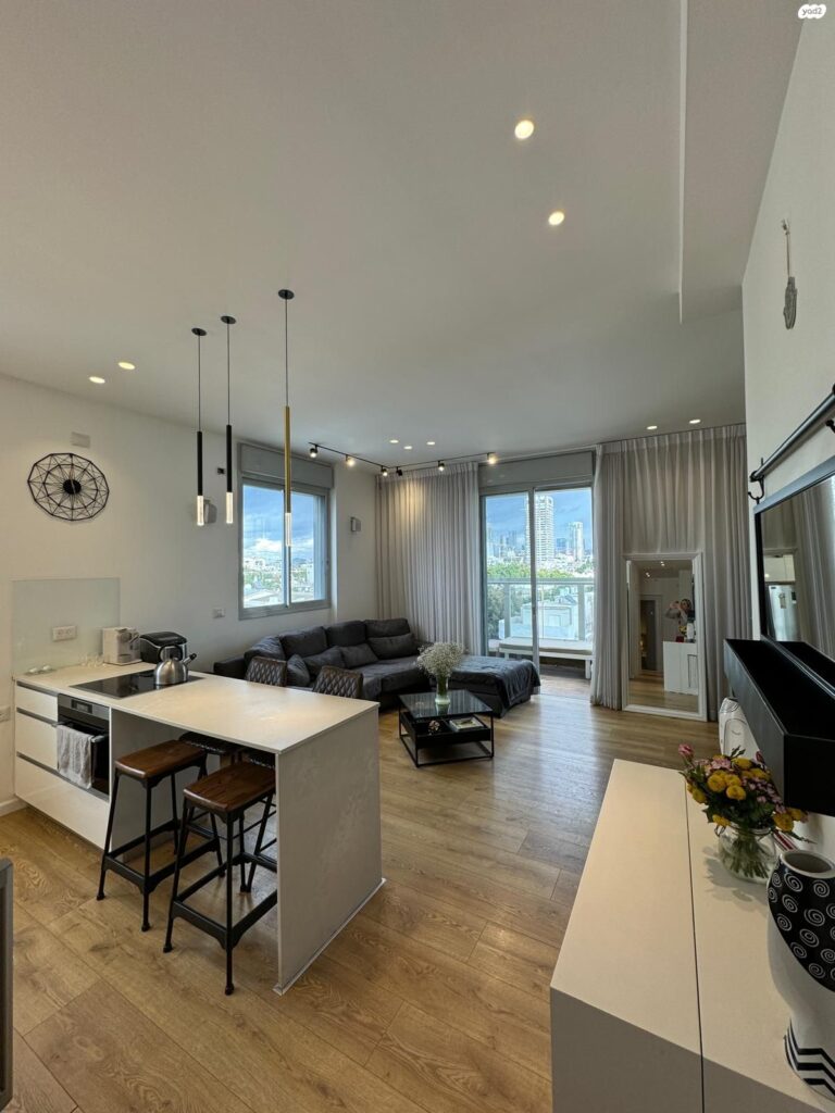 Spacious living area with floor-to-ceiling windows and wood flooring