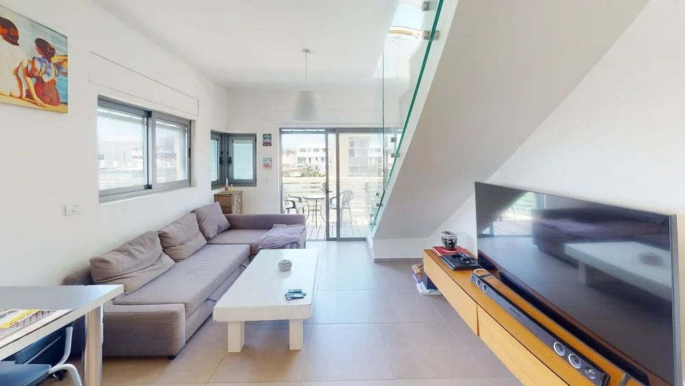 Bright penthouse living room with TV and sliding doors to balcony