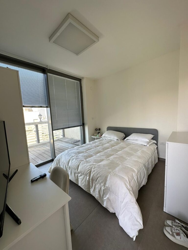 Minimalist bedroom with sliding glass doors to private balcony