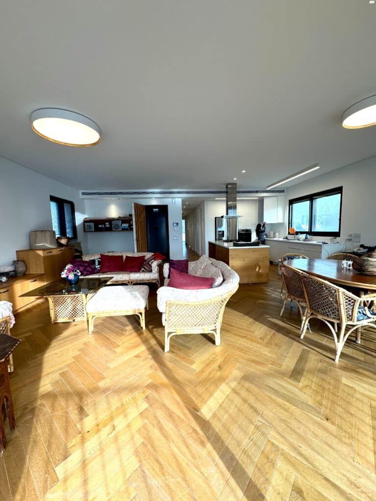 Open-plan living room with natural light and hardwood floors in Tel Aviv apartment