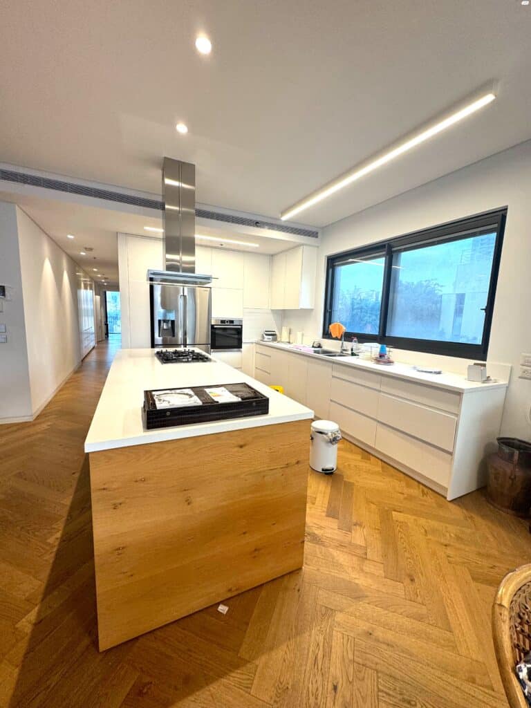 Modern kitchen with large island and built-in appliances in Tel Aviv apartment