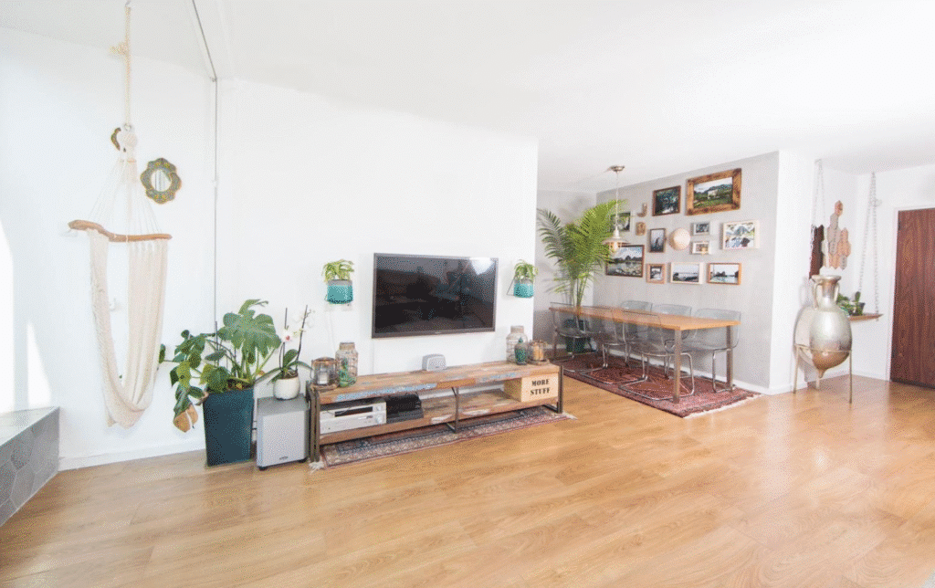 Open-concept living and dining room with plants and decor in Tel Aviv flat