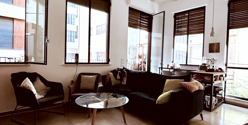 Bright living room with sofa and large windows in Tel Aviv apartment