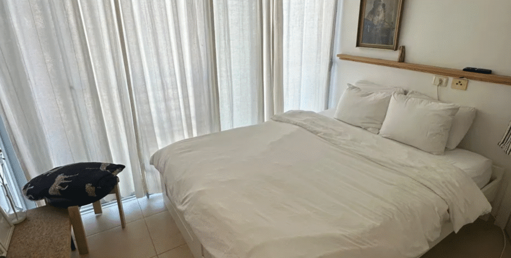 Cozy bedroom with white linens and floor-to-ceiling curtains