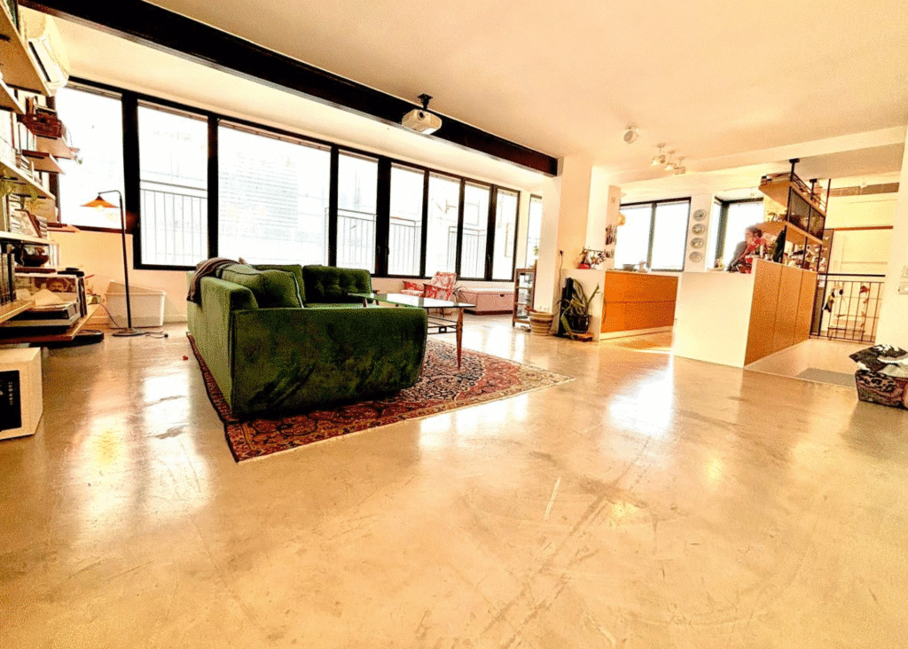 Spacious living area in architect-renovated Tel Aviv penthouse with green velvet sofa