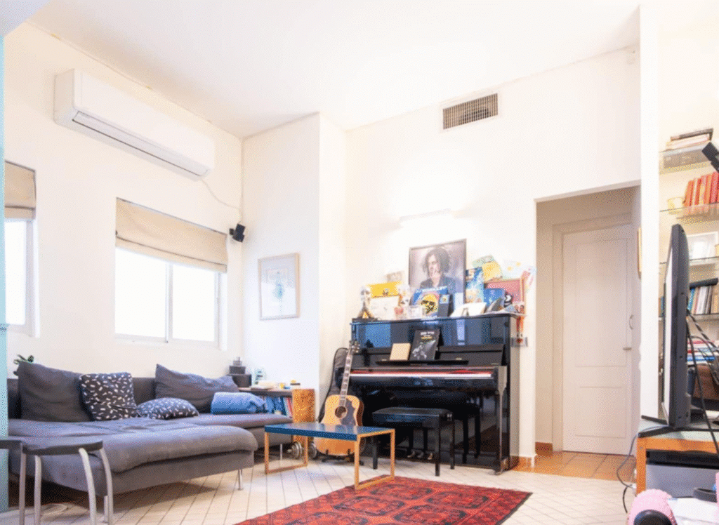 Cozy living room with piano, sectional sofa, and air conditioning
