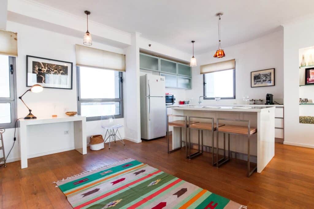 Open-plan kitchen with island and bar stools in Tel Aviv rental apartment