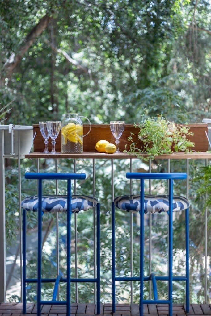 Balcony with blue bar stools and treetop view in Tel Aviv apartment