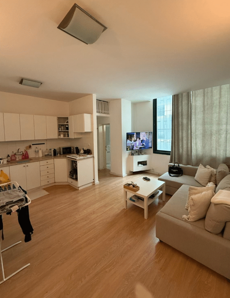 Spacious living area with sectional sofa and mounted TV in Tel Aviv apartment