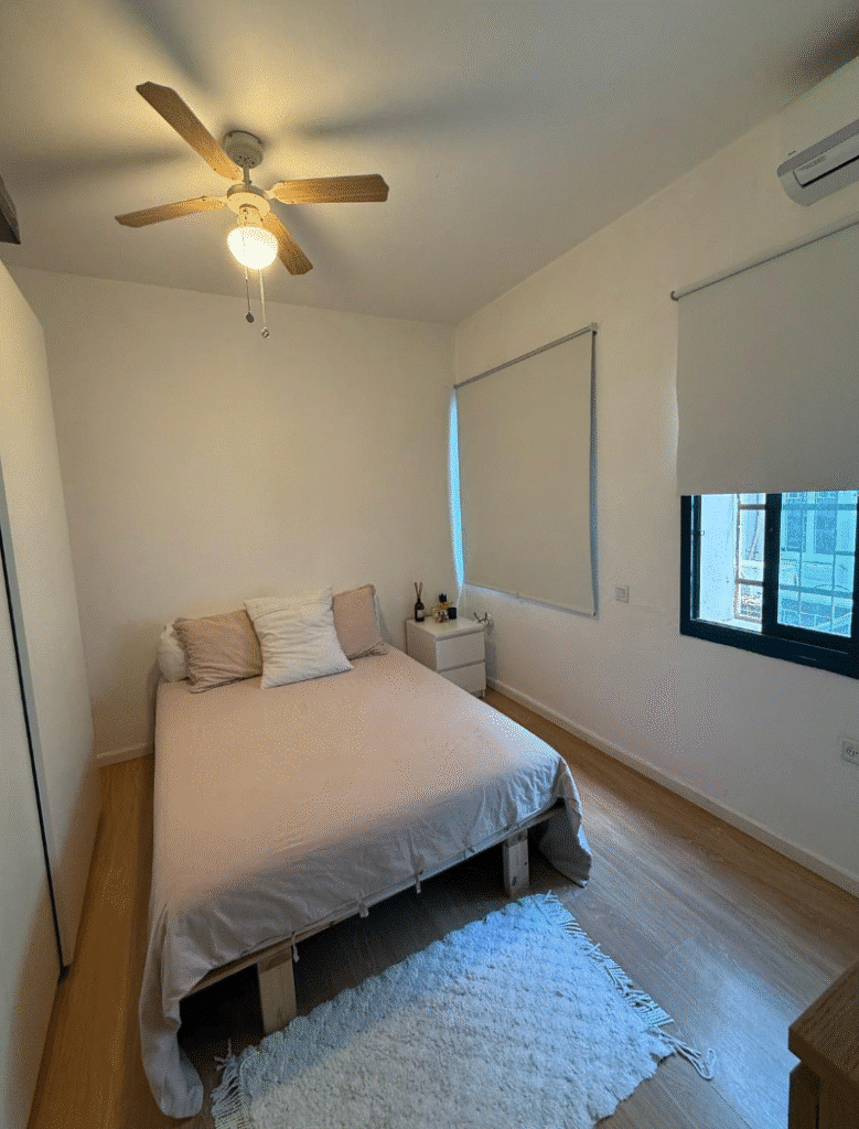Bright bedroom with double bed and ceiling fan in Tel Aviv flat
