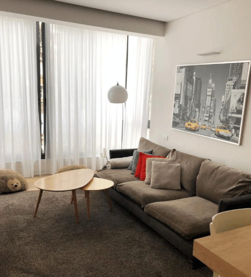 Sunlit living room with sheer curtains and cozy seating area in Tel Aviv
