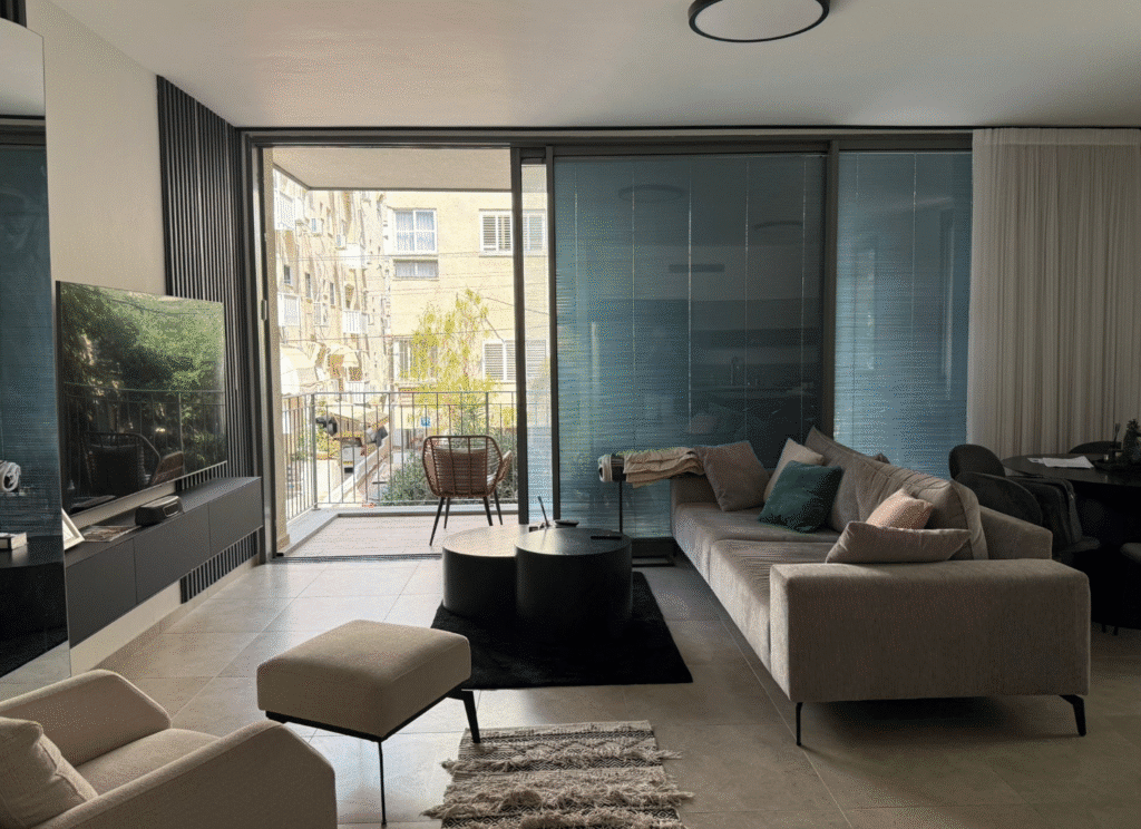 Spacious living room with modern furniture and access to balcony in Tel Aviv apartment