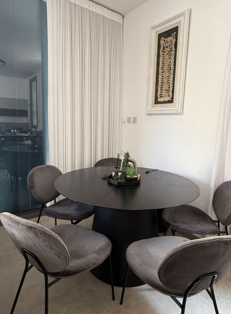 Stylish dining area with round black table and velvet chairs