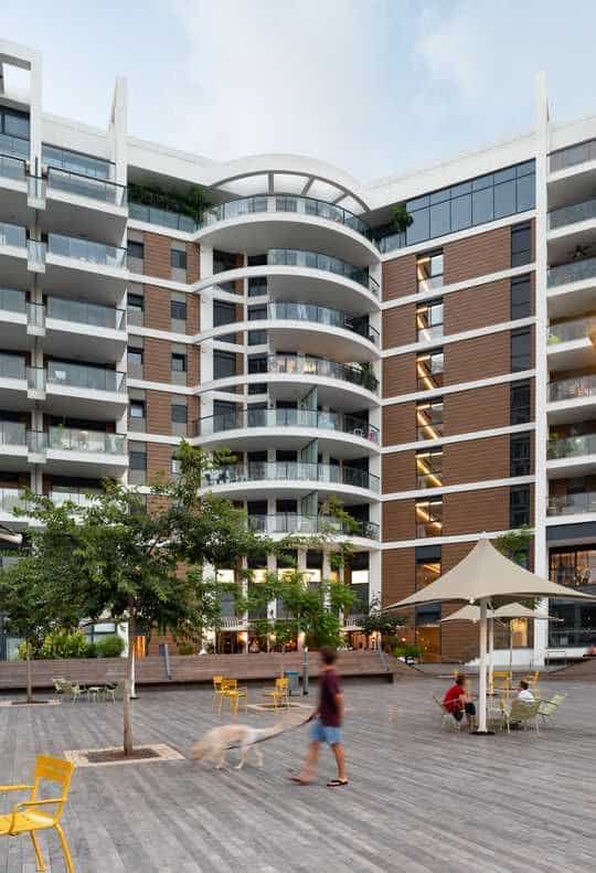 Modern luxury apartment building with balconies and open plaza in Tel Aviv