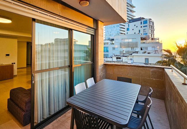 Private balcony in Tel Aviv apartment with outdoor dining set and sunset view