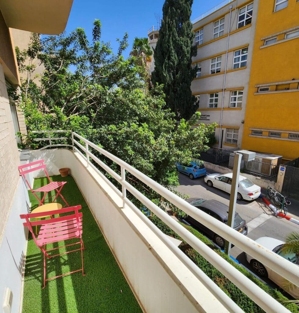 Balcony with greenery and colorful chairs overlooking Tel Aviv street