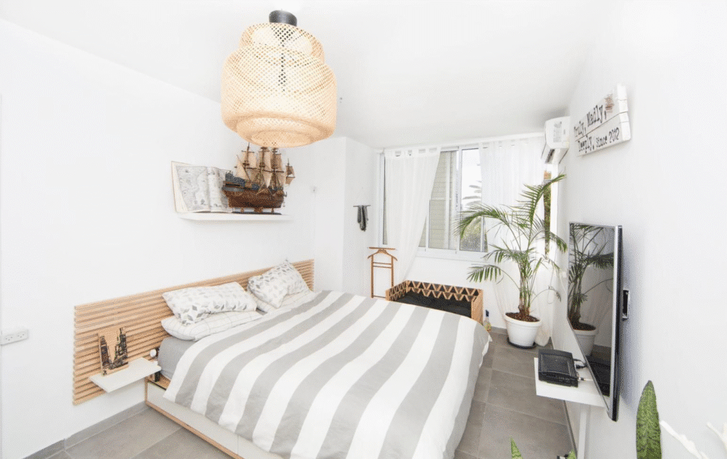 Bright bedroom with natural tones and greenery in Tel Aviv home