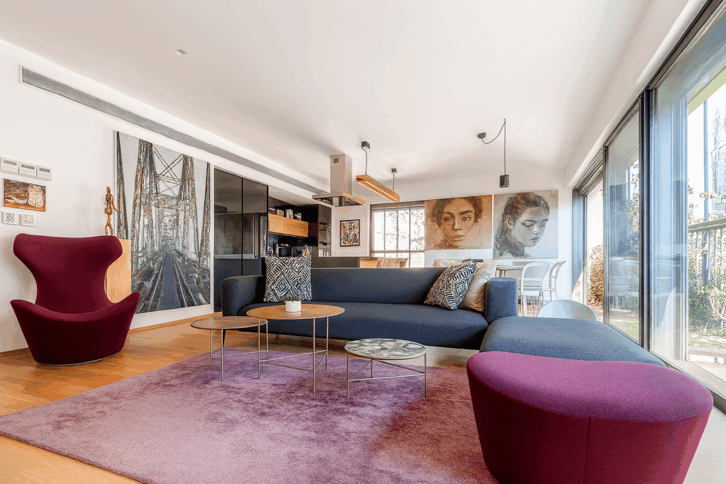 Spacious open-plan living room with large windows and modern art in a Tel Aviv penthouse